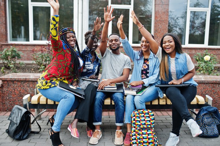 group five african college students spending time together campus university yard black afro friends studying bench with school items laptops notebooks Group of five african college students spending time together on